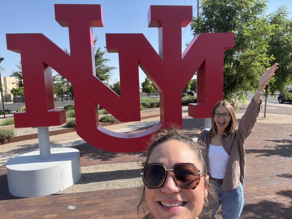 Megan and Kate in front of the UNM sign.