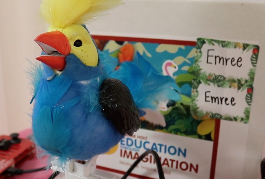 Example of an animatronic bird in front of a box displaying the text "Education Through Imagination"