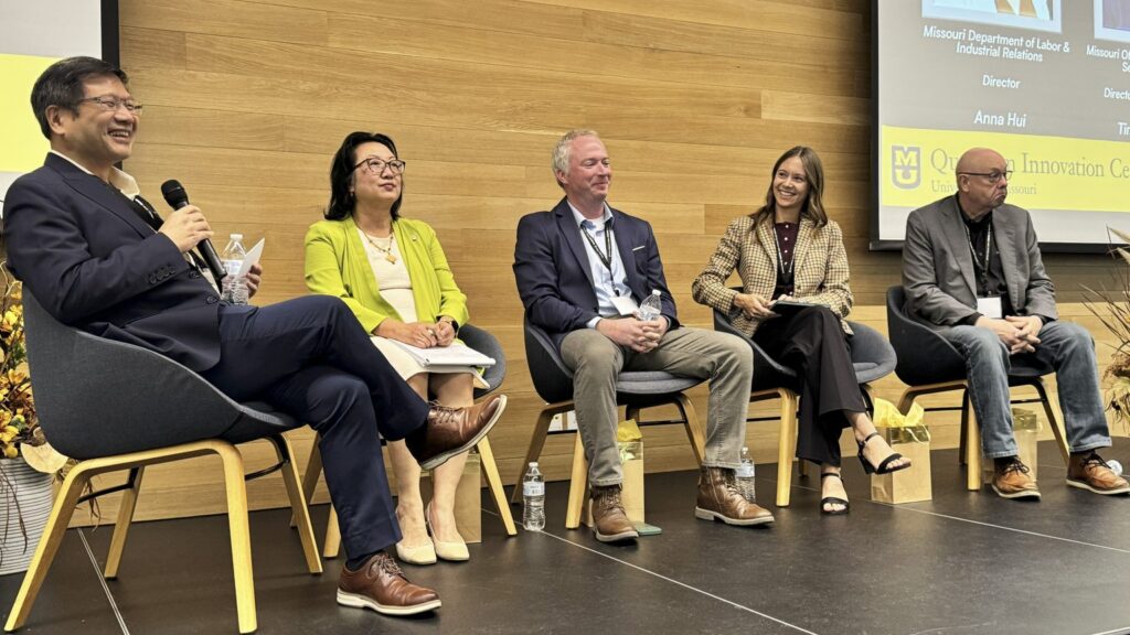 Speaker and 4 panelist on a stage.